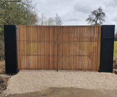 Moderne houten poort met stalen accenten op de oprit van een woning