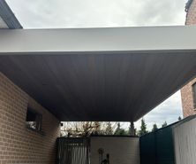 Moderne stalen carport met een plat dak en houten plafond